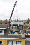 Een dakkapel wordt met een hijskraan geplaatst op het dak van een rijtjeswoning in Vlietestein, Nieuw-Vennep