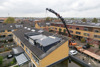 Een dakkapel wordt met een hijskraan geplaatst op het dak van een rijtjeswoning in Vlietestein, Nieuw-Vennep